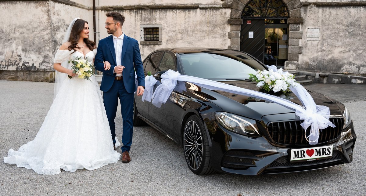 Poročni par pred Mercedes vozilom